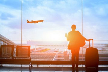 person_at_airport_holding_coffee_and_luggage