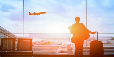 person_at_airport_holding_coffee_and_luggage