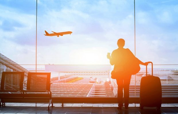 person_at_airport_holding_coffee_and_luggage