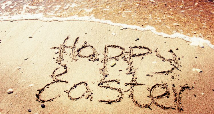 Happy Easter written on a sandy beach